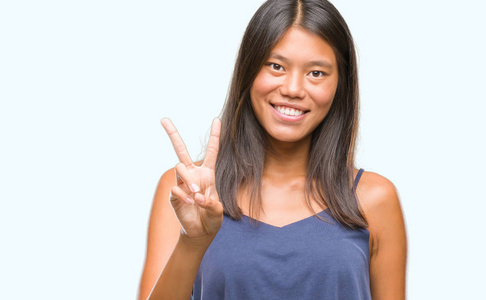 在孤独的背景下, 年轻的亚洲妇女微笑着快乐的脸眨眼在相机做胜利标志。第二个