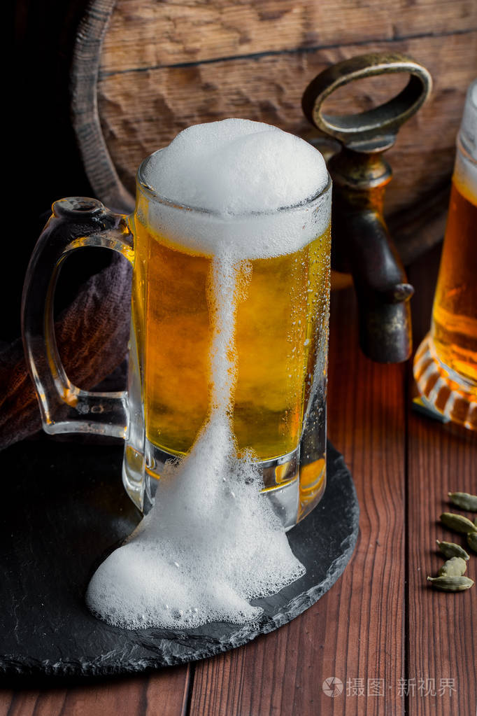旧背景玻璃上的轻泡沫啤酒