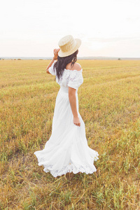 美丽的年轻女子在白色礼服领域, 软的焦点背景