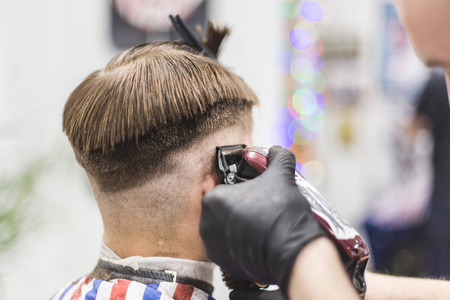 理发店的男士理发。理发师傅给客户理发。使用剪刀和剪。工作流的特写