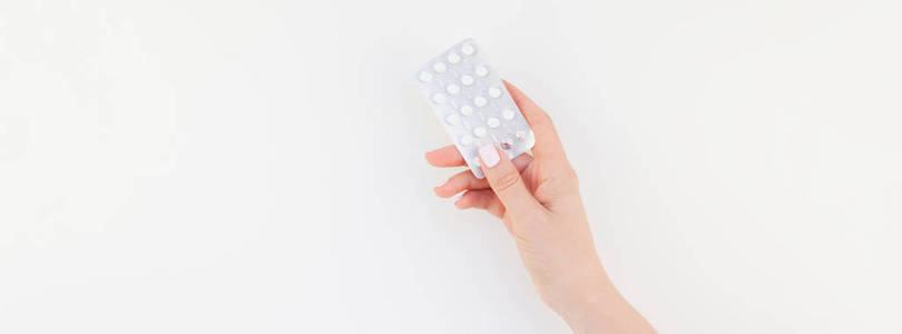 女人手用粉彩指甲抛光在白色背景与复制空间隔离的水泡药片。长宽横幅为女性美丽博客社交媒体。女性保健理念