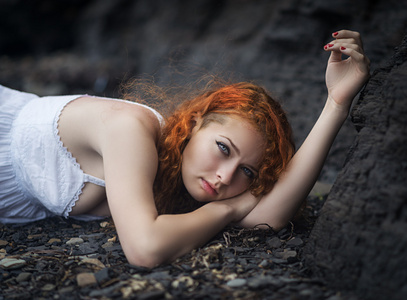 红发女人躺下来在砂砾上图片