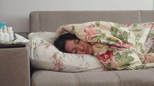 躺在床上裹着毯子的年轻女子照片