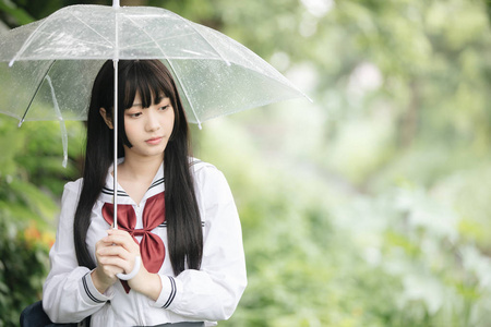 在雨中漫步在自然人行道上的亚洲学校女孩肖像