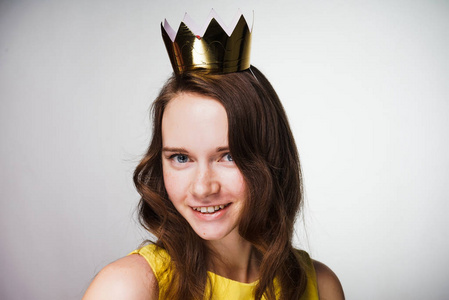 美丽的年轻女子穿着黄色的礼服看着相机和微笑, 在她的头上的金色皇冠