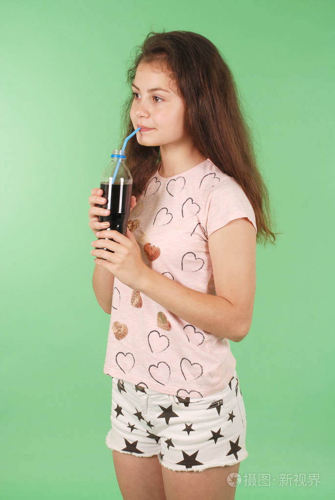 美丽的年轻女孩手捧可乐在瓶在绿色背景下隔离