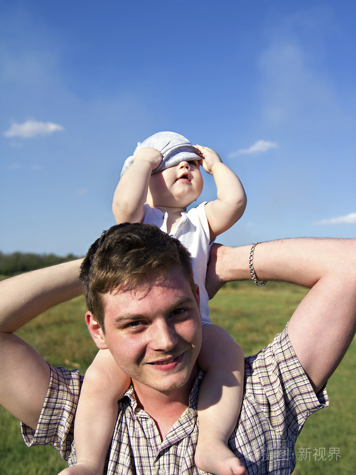 父亲抱着小的孩子在他的肩上