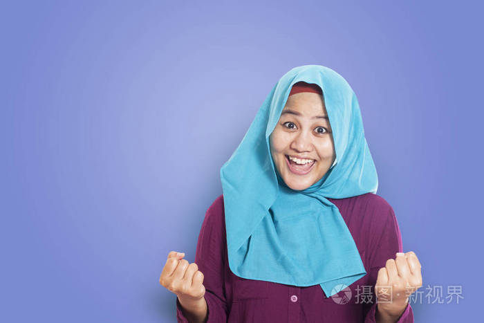 成功的肖像美丽的穆斯林女商人戴头巾显示赢得胜利 gesturover 蓝色
