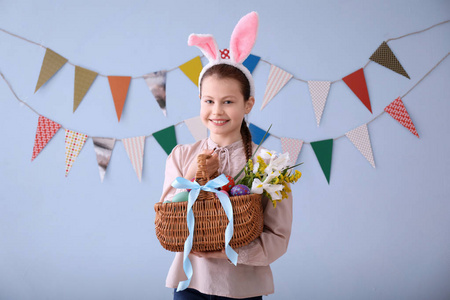 可爱的小女孩抱着柳条篮子满是复活节彩蛋墙上装饰党锦旗