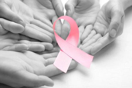 女性手与粉红色丝带在光背景, 特写镜头。乳腺癌概念