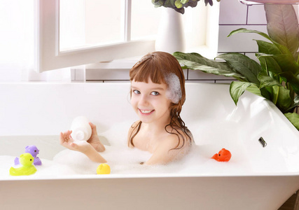 快乐的小女孩坐在浴缸里的浴室