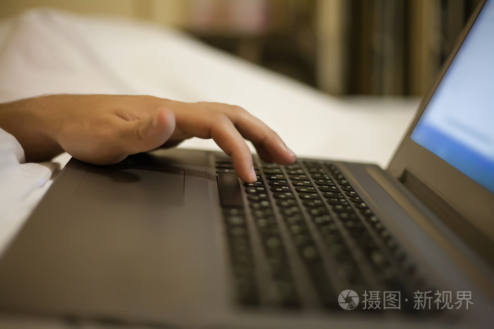 男子躺在床上笔记本电脑上按下键