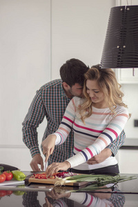 快乐的年轻夫妇，一起在家里的厨房里煮饭的肖像