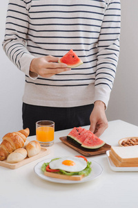 早晨在家吃早餐的人与三明治和果子