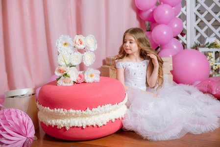 金发碧眼的小女孩庆祝生日快乐党与玫瑰装饰和气球