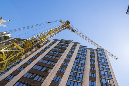 用起重机建造高层建筑。建筑施工用模板。蓝天下的起重机和建筑物