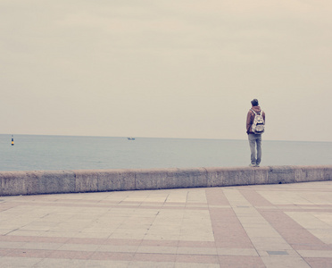一名年轻男子站在江边，望着大海