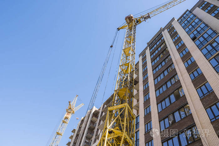 用起重机建造高层建筑.建筑施工用模板.蓝天下的起重机和建筑物