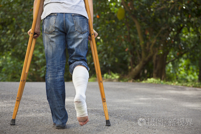 亚洲年轻男子拄着拐杖与树背景