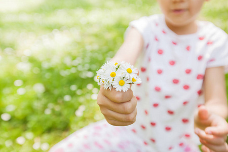 快乐的小女孩在自然与菊花花束在花草甸, 美丽的春天天