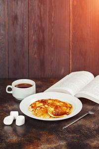 白盘子蜂蜜煎饼, 茶和棕色背景书