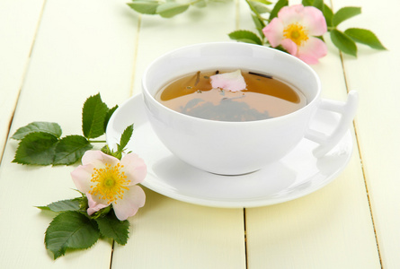 杯与髋关节月季花白色的木桌上的花草茶