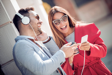 浪漫情侣用手机和在街上听音乐的肖像