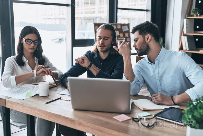 一群年轻的现代人在聪明的休闲穿着一起工作, 而坐在创意办公室