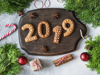 姜圣诞节或新年饼干的形式, 在灰色背景的深色木板上的数字2019。季节性包装和新年的特点。顶部视图