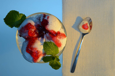 甜点勺与白色冰淇淋和红色果酱在盘子附近与冰淇淋