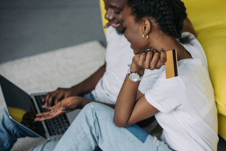 与笔记本电脑和信用卡购物在线微笑年轻的非洲裔美国人夫妇裁剪拍摄