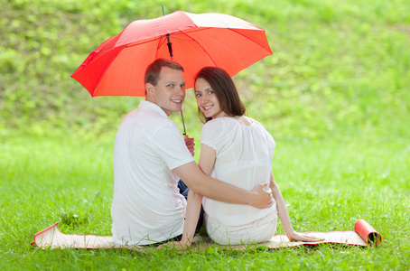 快乐微笑在红伞下的年轻夫妇