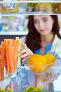 女性站附近打开冰箱充分的健康食品，蔬菜和水果的画像。女性肖像