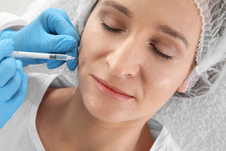 妇女在诊所得到面部注射。整容手术理念