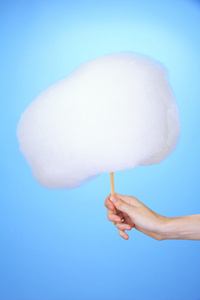 在彩色背景上拿棍子与棉花糖的手照片