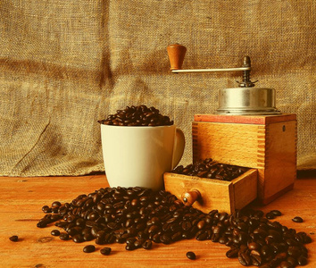 老式咖啡壶, 咖啡豆和白杯填充咖啡豆的木质背景
