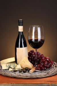 生活依然精致的酒 奶酪 柳条棕色背景上的木桌上的托盘上葡萄