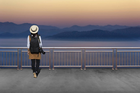 亚洲女性游客, 她穿着休闲风格的日本. 用简单的黑色背包和镜头后面看风景的秋季风景
