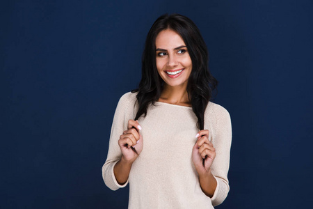 轻浮的美.美丽的年轻女子看着微笑,而站在反对黑色背景照片