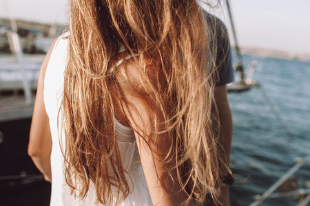 年轻幸福的情侣, 女孩在日落附近的游艇在海边飞的头发