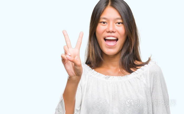 在孤独的背景下, 年轻的亚洲妇女微笑着快乐的脸眨眼在相机做胜利标志。第二个