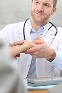 去看医生。医生通过握住他的手腕检查病人的心率。