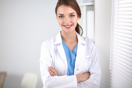 一位女大夫站在窗口与双臂交叉附近照片