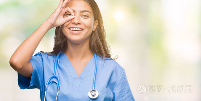 年轻的阿拉伯医生外科医生妇女在孤立的背景做 ok 手势与手微笑, 眼睛看通过手指与幸福的脸