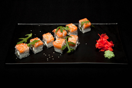 寿司卷与鲑鱼和鳄梨在板上黑色背景顶部视图