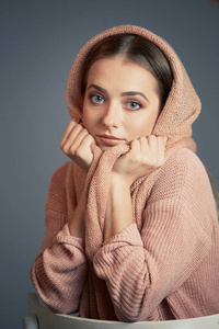 一个美丽的女孩在一个灰色的背景在工作室针织粉红色头巾的大情感肖像
