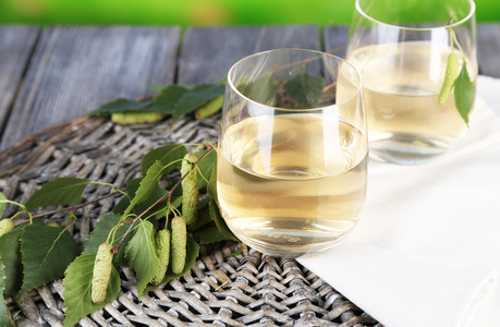 glass 木制的桌子上的白色和蓝色的背景上新鲜的白桦树汁照片