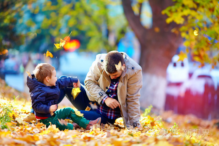 快乐的父亲和儿子在秋天公园玩乐