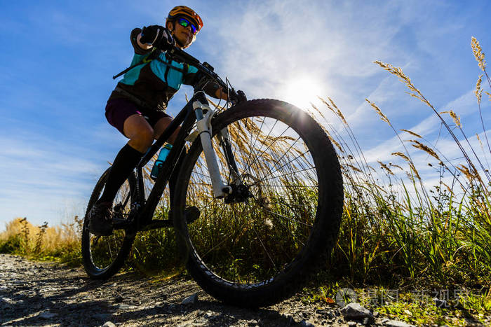骑自行车在秋天的树林中的小周期路上山关心他人女人山地自行车在秋天