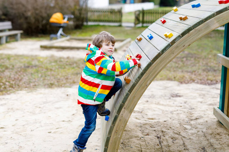 快乐的金发孩子男孩开心和室外操场上攀爬照片